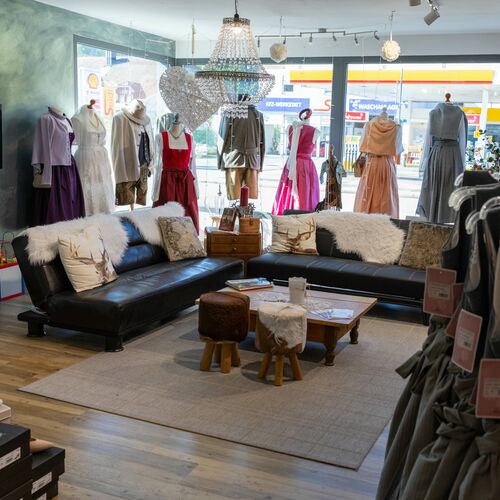 Gemütlicher Sitzbereich mit Sofas und Kinder-Spielecke, dahinter Schaufenster mit Trachtenoutfits und Dekoration