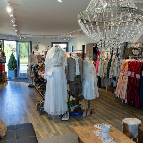 Verkaufsraum mit Brautdirndl, Trachtenanzug und traditionellen Kleidern auf Puppen in elegantem Ambiente mit Holzfußboden
