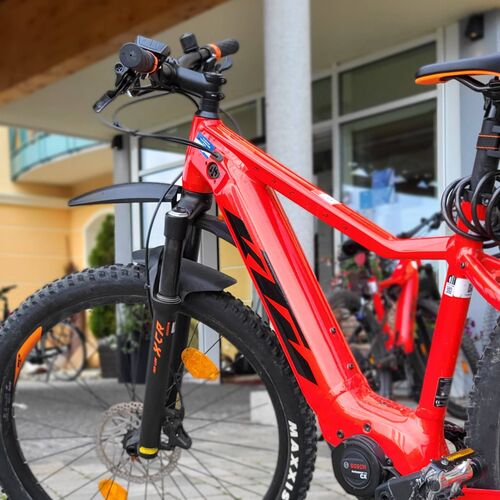 Rotes E-Mountainbike mit breiten Reifen und Bosch-Motor steht vor dem Hotel Stemp auf gepflastertem Boden.