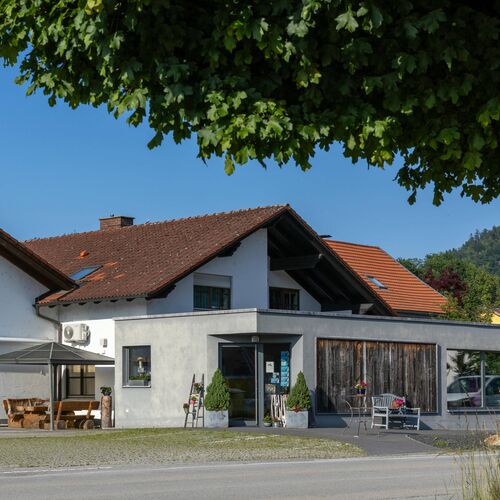 Außenansicht eines Trachtengeschäfts mit moderner Glasfront und traditionellem Hausdach bei sonnigem Wetter in Bayern